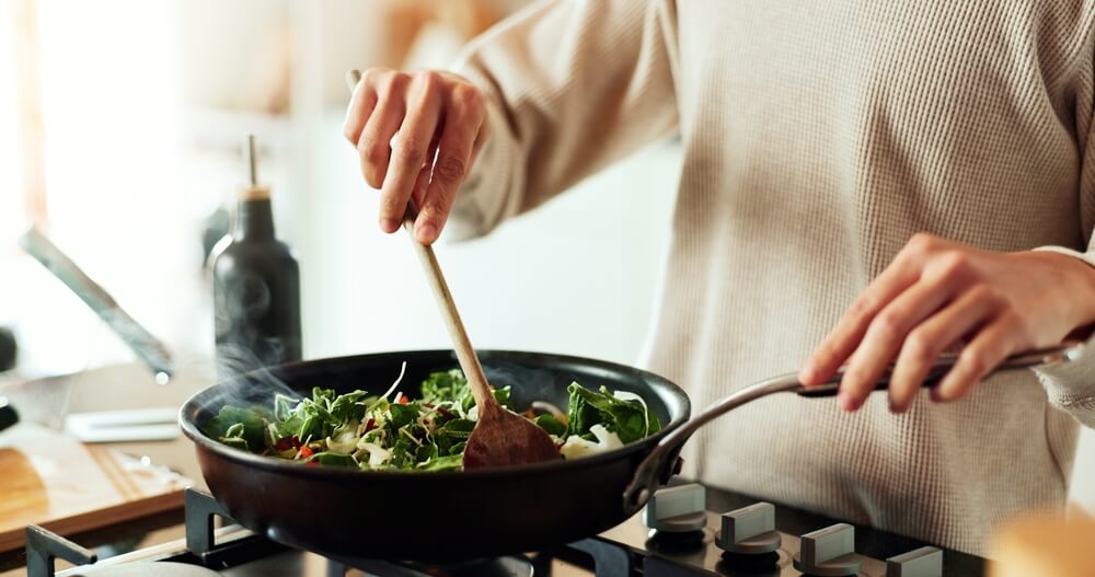 person cooks vegetable meal at a stove