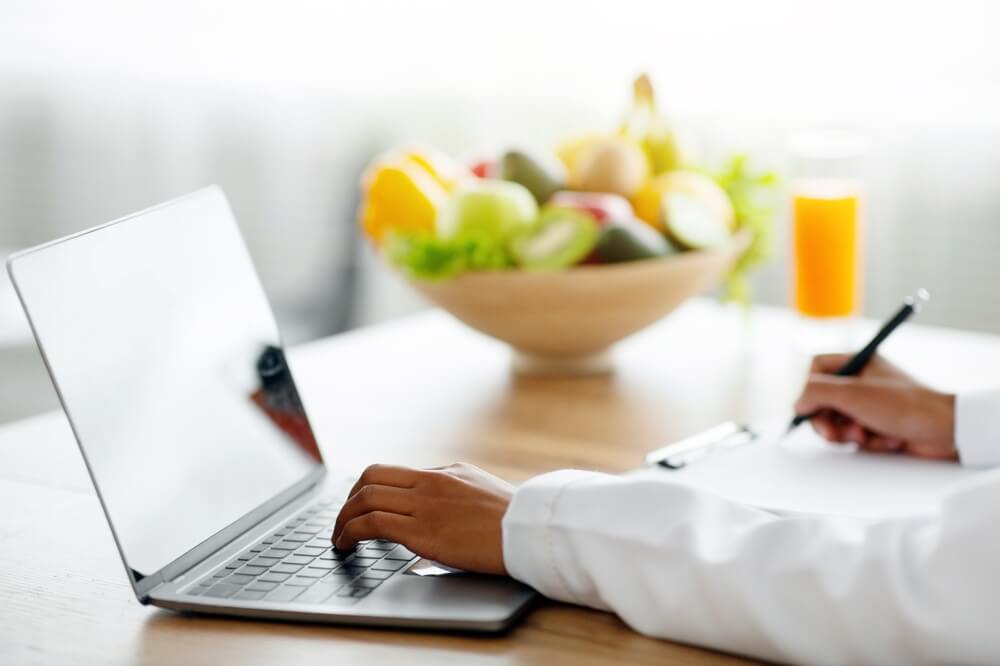 nutritionist works at a computer next to bowl of fruit